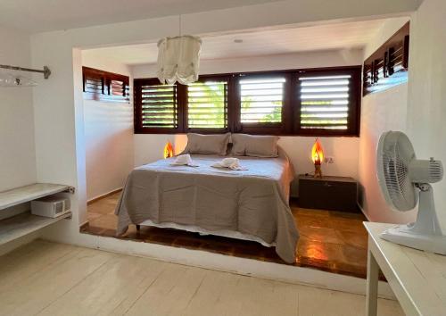 a bedroom with a bed with two lamps and a fan at Casa Ametista in Jericoacoara