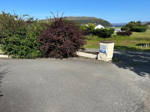 a road with a sign on it next to a bush at Feochan Portree in Portree