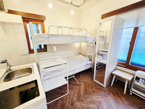 ソウルにあるGive Home Guesthouseの二段ベッド2台とシンクが備わる客室です。