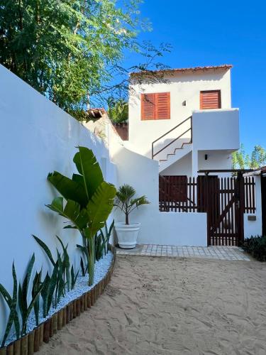ein weißes Haus mit einem Zaun und Pflanzen in der Unterkunft Casa Cristal in Jericoacoara