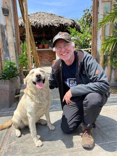 a man is kneeling next to a dog at Coco y Ainhoa Lodge in Paracas
