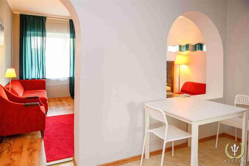 a living room with a white table and a red chair at Neptun Ψ Resort in Jastrzębia Góra
