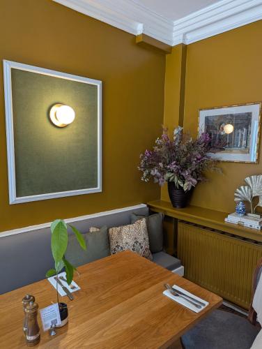 a dining room with a table and flowers on the wall at The Duke Hotel in Hilmarton