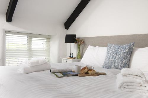 a white bed with a teddy bear and a book on it at Cape Cornwall Club in St. Just