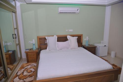 a bedroom with a bed with white sheets and pillows at HOTEL La BASE228 in Komé