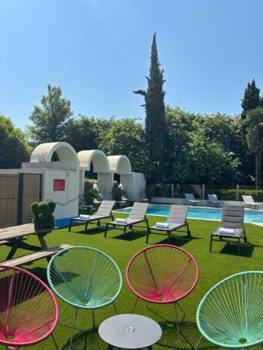 a group of chairs and tables on the grass near a pool at Ibis Styles Cognac in Châteaubernard