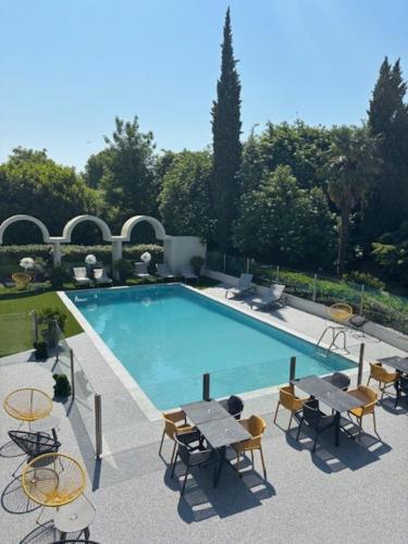 a swimming pool with tables and chairs next to it at Ibis Styles Cognac in Châteaubernard