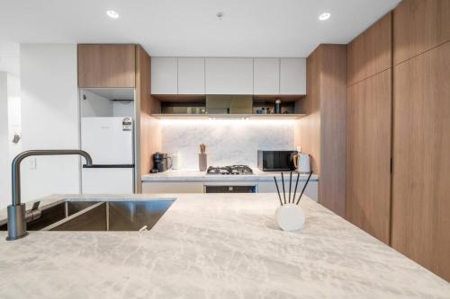 a kitchen with a counter with a sink and a refrigerator at Queen's Wharf - Lv48 2Bedroom apt next to the Star in Brisbane