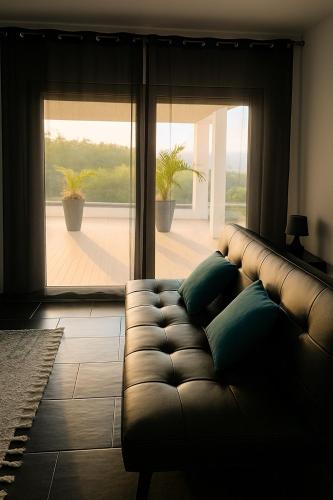 a leather couch in a living room with a large window at Batalha Village View in Batalha