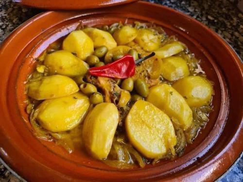 a bowl of food with potatoes and peas and a red pepper at Cafe Restaurant Moove Oil in Rissani