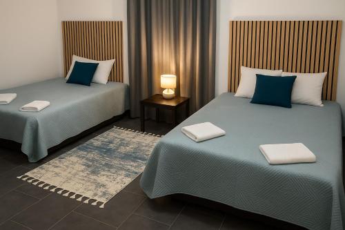 two beds in a hotel room with blue pillows at Batalha Village View in Batalha