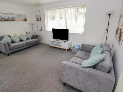 a living room with two couches and a television at Awel-Y-Mor in Swansea