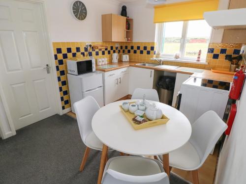 a small kitchen with a white table and chairs at Awel-Y-Mor in Swansea