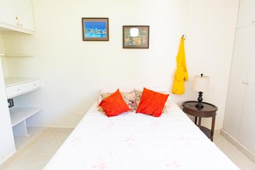 a bedroom with a white bed with red pillows at 1 block from the Ocean, comfy condo with pool view in Progreso