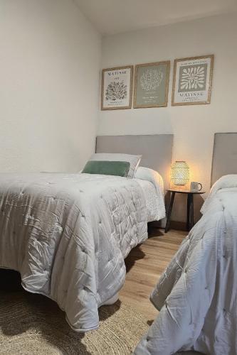 two beds with white comforters in a bedroom at Chez Marie in La Muela
