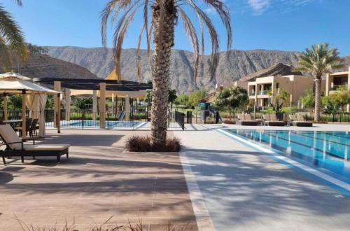 a resort with a palm tree and a swimming pool at Two bedroom Apartment Muscat Bay in Muscat