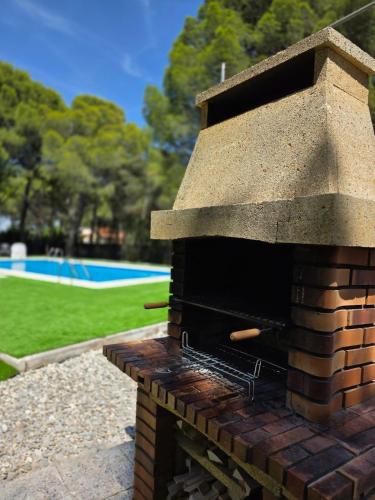an outdoor brick pizza oven with a pool in the background at Chez Marie in La Muela