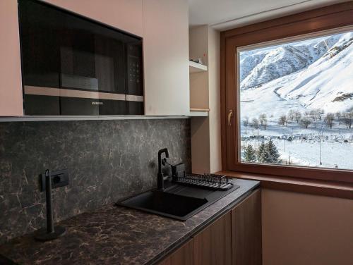 eine Küche mit Spüle und einem Fenster mit einem schneebedeckten Berg in der Unterkunft Cervinia Exclusive in Breuil-Cervinia