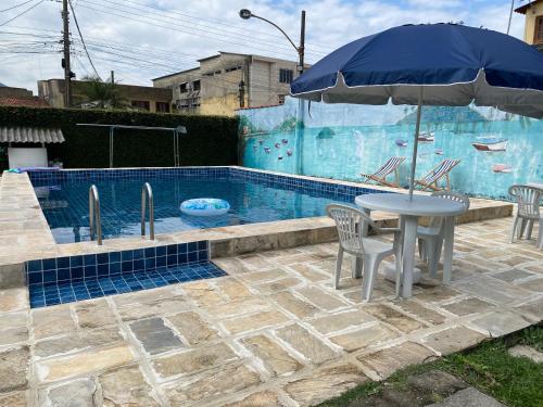 a table with an umbrella next to a swimming pool at Pousada Recanto dos Leporage Itacuruçá in Mangaratiba