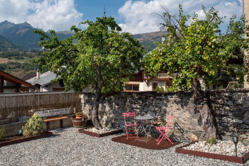 a patio with two chairs and a table on a stone wall at Maison Lennox in Mâcot La Plagne