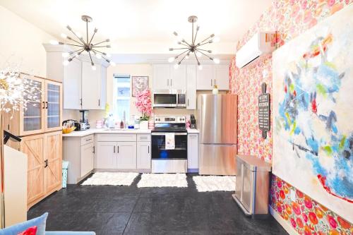 a kitchen with white cabinets and a painting on the wall at I- Lovely Family Home Near Universal with Patio and Games in Sepulveda