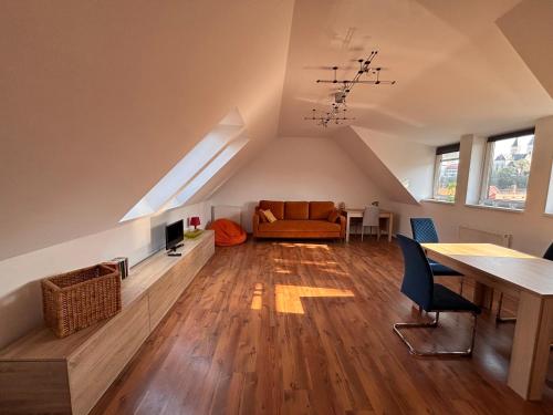 an attic living room with a couch and a table at Séd Völgye Apartman in Veszprém