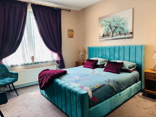 a bedroom with a large blue bed with purple pillows at Super King, Close to Beach, Shops, Train, Shared Bathroom in St. Leonards
