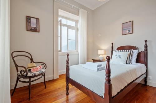 a bedroom with a bed and a chair and a window at Villa Rosa Mare by Homie in Seixal