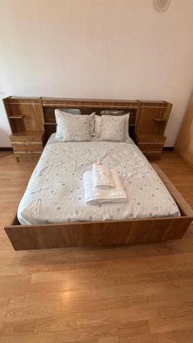 a bed with a wooden frame with a book on it at Quarto com varanda no centro de viseu in Viseu