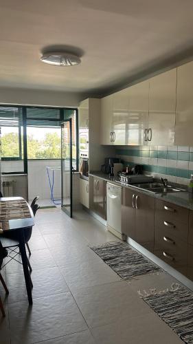 a kitchen with white cabinets and a table in it at Quarto com varanda no centro de viseu in Viseu