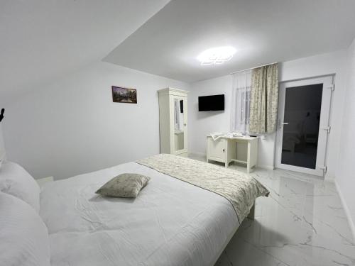 a white bedroom with a bed and a window at Casa IL LUCE in Câmpulung Moldovenesc