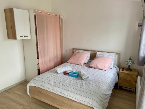 ein Schlafzimmer mit einem Bett mit rosa Kissen in der Unterkunft Maisonnette cosy au calme terrasse local vélo in Rochefort