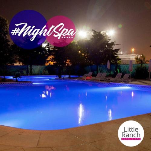 a large swimming pool at night with a lit up sign at Little Ranch Hotel Spa Pilar in Manuel Alberti