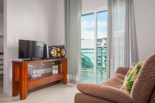 Una sala de estar con un televisor de pantalla plana y un sofá. en CF · Cabo Frio Relax!, en Cabo Frío