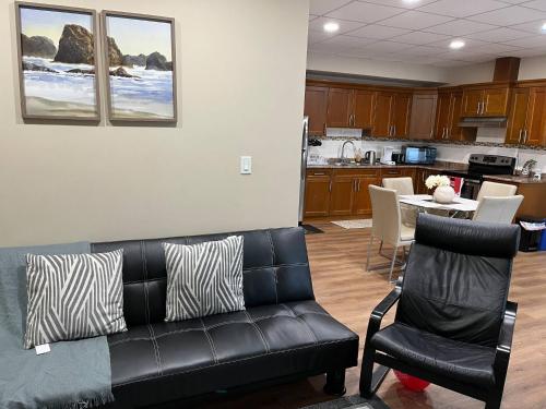 un salon avec un canapé noir et une cuisine dans l'établissement Tranquille pond facing suite, à Nisku