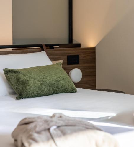a bedroom with a bed with a green pillow at Alchimia WellResort in Comano Terme