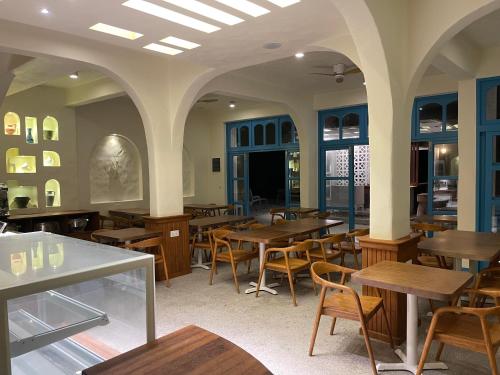 Un restaurante con mesas y sillas de madera y ventanas. en Endorphins Beach Villa, en Dhiffushi
