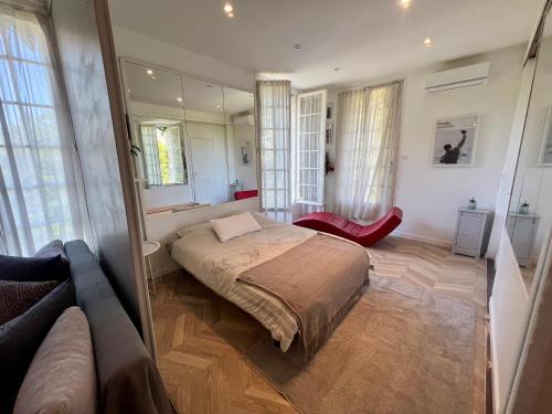 a bedroom with a bed and a couch and windows at Lumineux appartement, jardin, vu sur mer in Trouville-sur-Mer