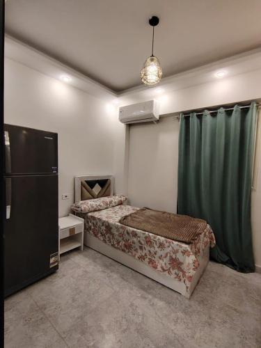 a bedroom with a bed and a refrigerator at فندق العجمي 68 in 6th Of October