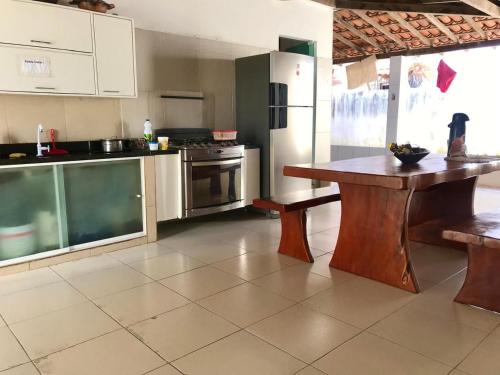 a kitchen with a wooden table and a refrigerator at Casa Luxuosa Ponta de Aratuba in Vera Cruz de Itaparica