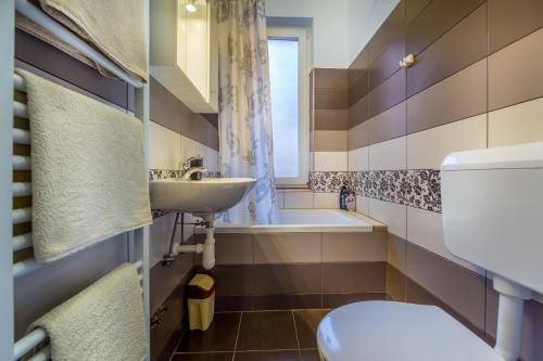 a bathroom with a toilet and a sink and a tub at Rooms Center Demetrova in Rijeka