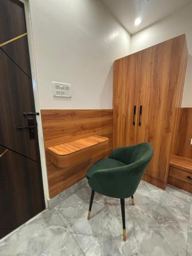 a room with a green chair and a wooden cabinet at The Golden Inn in Lucknow