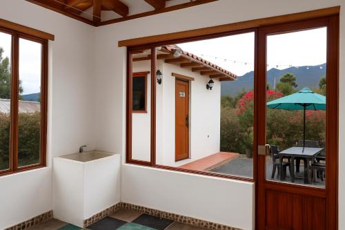 a room with a door and a table with an umbrella at Cabaña familiar con 2 dormitorios y baños privados in Villa de Leyva