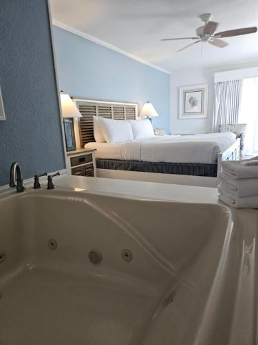 a bathroom with a bath tub and a bed at Surf Side Hotel in Nags Head