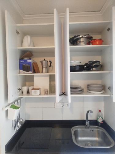 a kitchen with a sink and a shelf with dishes at Apartamento Rey-Piscina in Denia