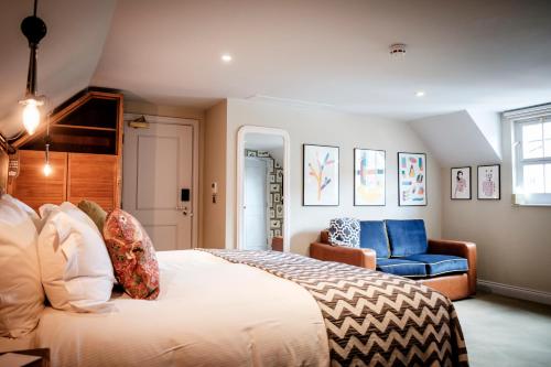 een slaapkamer met een groot bed en een blauwe stoel bij The Queen's Head in Kingston upon Thames