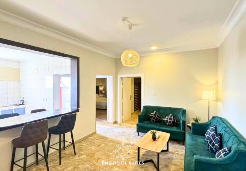 a living room with green furniture and a kitchen at البندقية للخدمات الفندقية BQ HOTEL SUITES in Buraydah