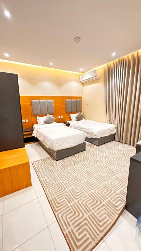 a hotel room with two beds and a carpet at شقق تالا للوحدات السكنية Furnished Units Tala in AlUla