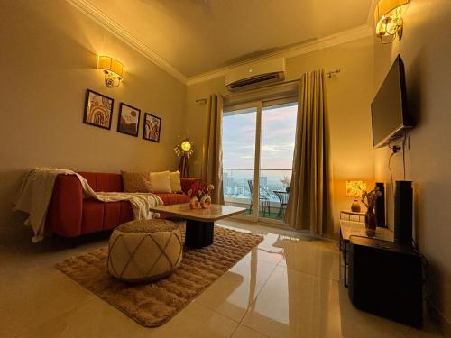 a living room with a red couch and a large window at Valley of us in Sohna