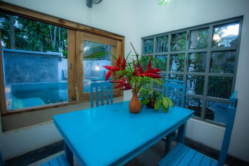 a blue table with a vase of red flowers on it at Percy Residence in Unawatuna